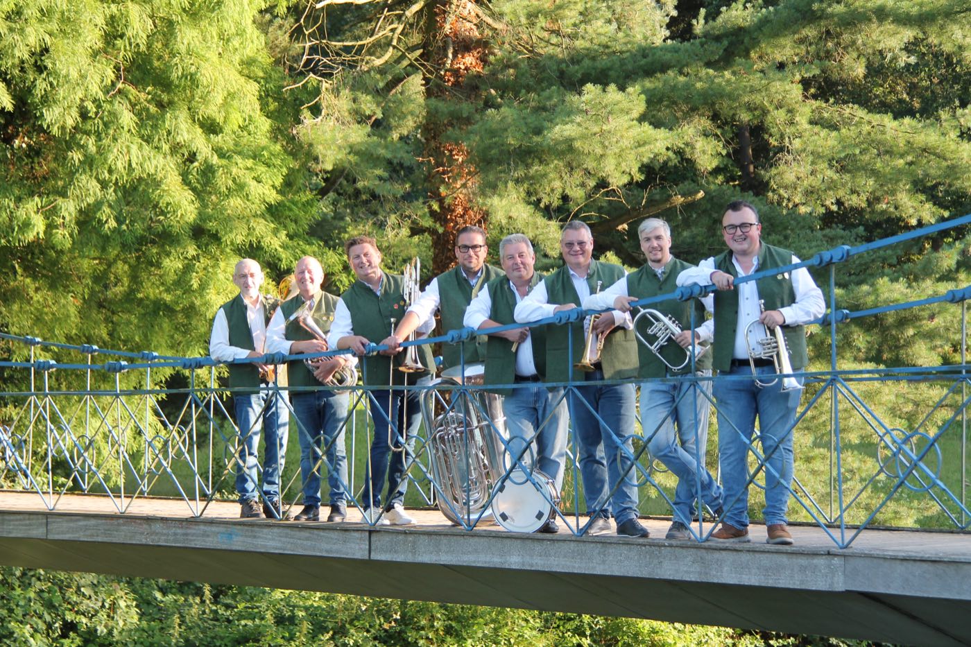 De muzikanten van BOM 2026 in hun groene vest, met hun instrumenten op een brug